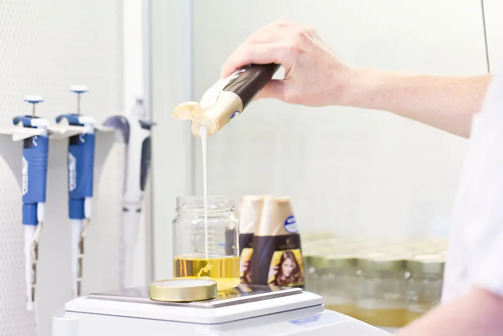 Shampoo is being poured into a container that is standing on a scale.